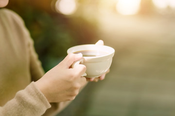 Young woman holding a cup of hot coffee in nature view