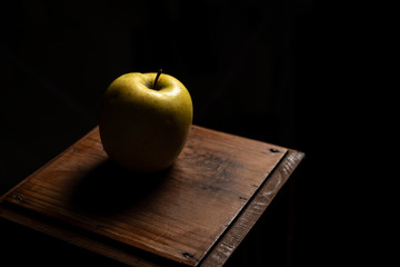 Manzana sobre mesita de madera y fondo negro