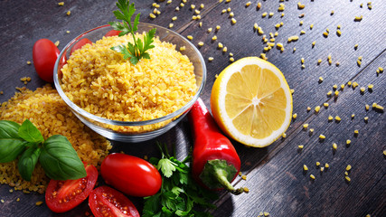 Bowl of uncooked bulgur on wooden table