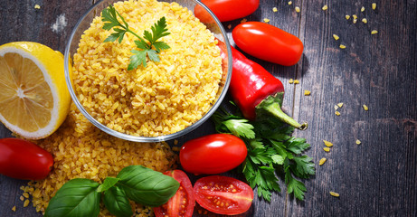 Bowl of uncooked bulgur on wooden table