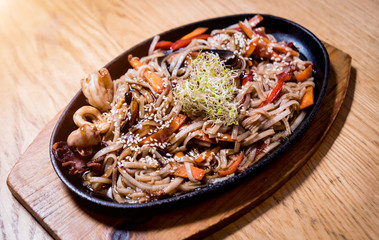 Chinese noodles with mussels and shrimps on the wooden table.