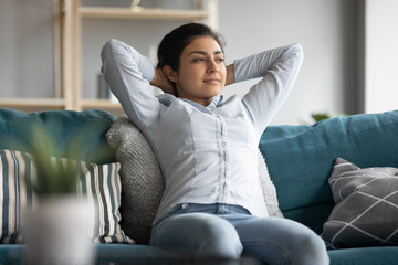 Happy ethnic woman relax on couch enjoying weekend