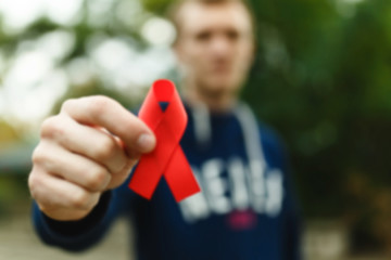 red aids ribbon in hand on green background, HIV