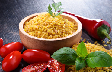 Bowl of uncooked bulgur on wooden table