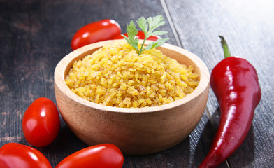 Bowl of uncooked bulgur on wooden table