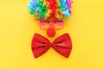 Fototapeta na wymiar carnival, party and Purim celebration concept (jewish carnival holiday) with clown wig, glasses and red nose over yellow background