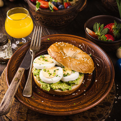 Healthy freshly baked bagel filled with boild eggs, avocado and chives. Breakfast food.