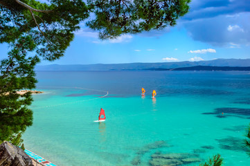 Windsurfer auf Surfbrettern im türkisfarbenen Meerwasser in der Nähe von Zlatni Rat oder Golden Horn Beach in der Stadt Bol auf der Insel Brac, Kroatien