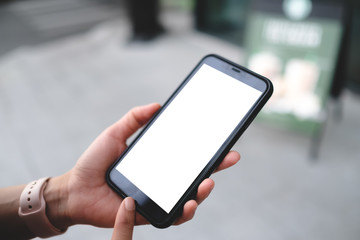 Closeup of male hand holding and using modern smart phone with blank screen for your text or content, with city bokeh