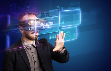 Businessman looking through Virtual Reality glasses with RENEWABLE ENERGY inscription, new technology concept