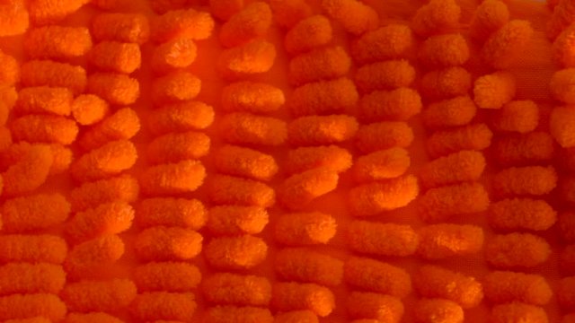 Beautiful microfiber cloth, bright orange microfiber. Microfiber texture with a soft large pile. Top view texture of orange big microfiber fabric towel