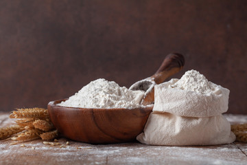 Wheat flour in cotton bag on wooden table. Ingredient for baking.