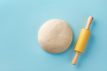 Dough and rolling pin on blue background top view. Bakery concept. Flat lay.