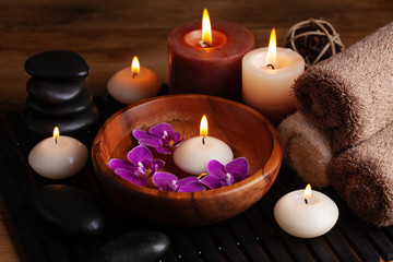 Obraz na płótnie Canvas Aromatherapy, spa, beauty treatment and wellness background with massage stone, orchid flowers, towels and burning candles...