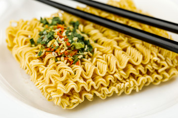 macro photography of dry instant noodle on plate with chopsticks