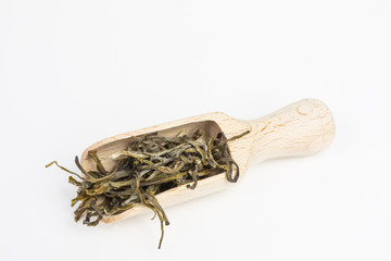 heap of dry leaves of white tea on a scoop