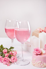 Two glasses with pink grape wine with rose flowers. Romantic dinner concept.