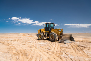 Yellow excavator on construction site, with the nice blue sky in the background.