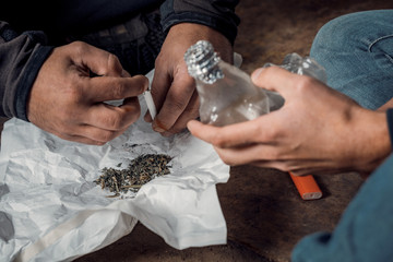 two shabby men preparing drug injection in slums