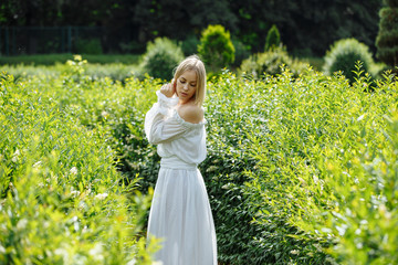 Fototapeta premium blonde in a white dress and a beautiful smile in the backlight