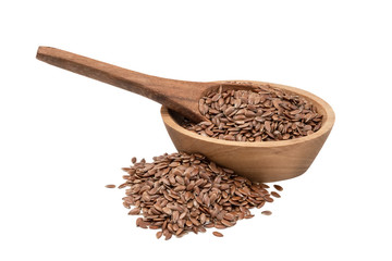 Linseeds or flax seed in a small oval wooden bowl with a spoon and pile next to it seen obliquely from the side and isolated on white background