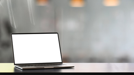 Fototapeta premium Photo of Computer laptop with white blank screen putting on modern counter with blurred comfortable living room as background.