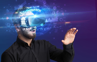 Businessman looking through Virtual Reality glasses with FINTECH inscription, innovative technology concept