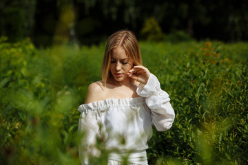 Fototapeta premium blonde in a white dress and a beautiful smile in the backlight