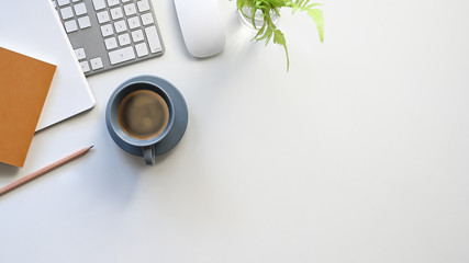 Above shot coffee cup, keyboard, mouse, notes, pencil and potted plant putting together on modern white table. Flat lay office equipment. Comfortable workplace concept. © Prathankarnpap