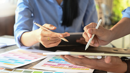 Cropped image of young graphic designer team holding/using a stylus pen and computer tablet while...