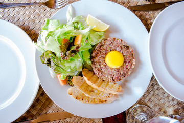 Steak Tartare with fresh organic vegetables serve on local table setting