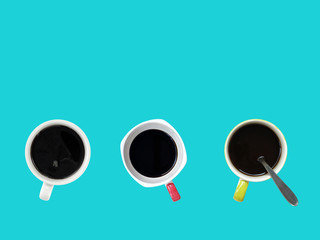 black coffee in three cups with silver stainless teaspoon isolated on blue