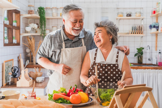 Lovely couple Asian elder happy and smiling cooking salad together for breakfast in the morning at home kitchen