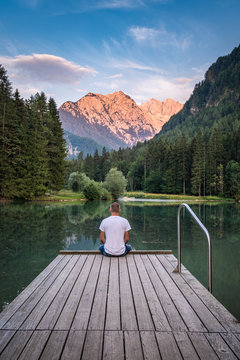 Man sits on landing stage, lake Planšarsko jezero, Zgornje Jezersko, Kamnik-Savinja Alps