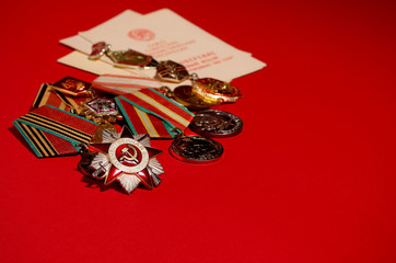 Order of the Patriotic war and a group of medals of the USSR. The medals and the order are on a red background.  May 9 Victory Day. Copy space