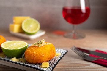 Homemade cheese croquettes on a plate with some lemon on the side.
