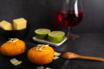 Homemade cheese croquettes on a plate with some lemon on the side.