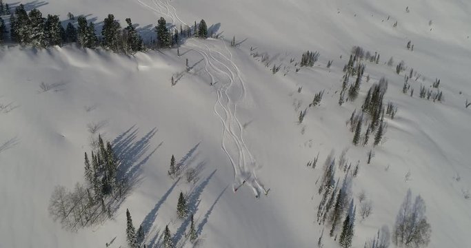 Aerial: a large group of free riders roll down the beautiful mountain valley. Freeride vacation and snowboarding ski resort. freeriding. snow cat during a day of cat skiing & heli ski location