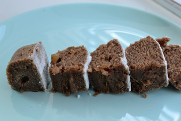 Brownies with raisins and icing sugar on a blue plate