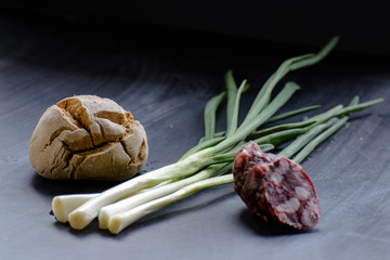 freshly baked bread, green onion and sausege on the dark table