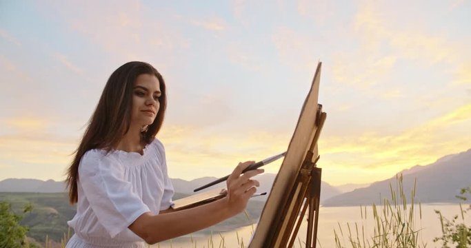 Experienced female artist enjoying her hobby, creating a picture inspired by beautiful landscape - recreational pursuit 4k footage