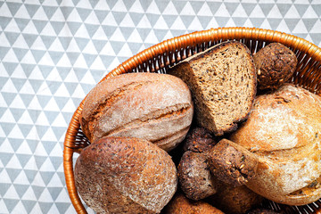 Fresh dark, grain and white bread in a basket on a tablecloth
