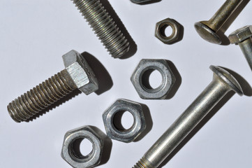 bolts and nuts of different sizes lie on a white background. top view.