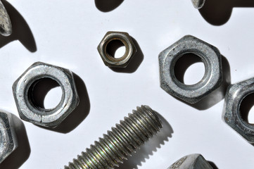 bolts and nuts of different sizes lie on a white background. top view.