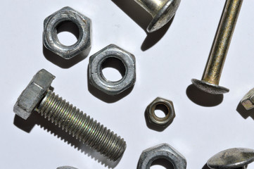 bolts and nuts of different sizes lie on a white background. top view.