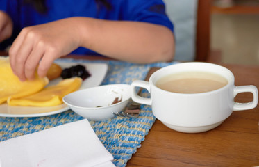 Cup or bowl of soup on blur plate with crape and jam and hand while eating breakfast