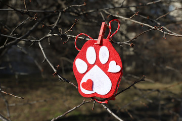 Martenitsa on a branch in shape of dog paw, dog love.