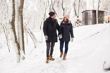 Fototapeta na wymiar christmas happy couple in love walking in snowy winter cold forest