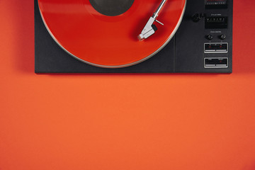 Colored vinyl record on a red background with copy space.
