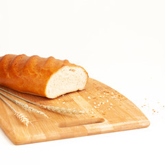 Wheat loaf on a cutting board with ears of wheat. Food, bakery products